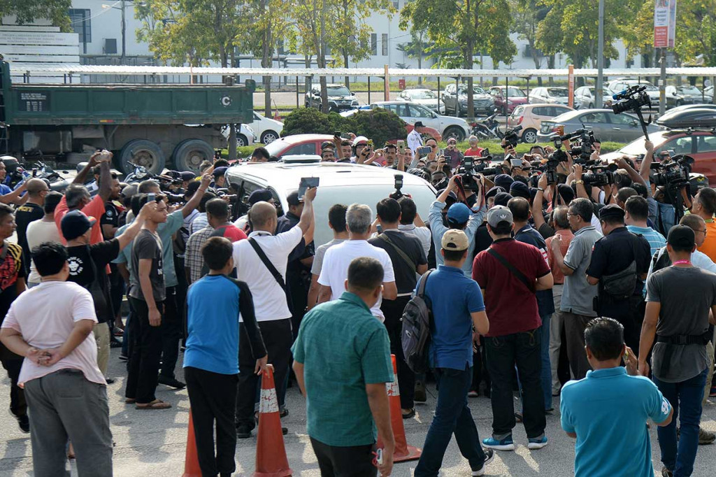 Puluhan orang mengerumuni mobil putih yang mereka duga membawa mantan PM Najib Razak saat tiba di Bandara Sultan Abdul Aziz Shah, Subang, Malaysia, Sabtu, 12 Mei 2018.