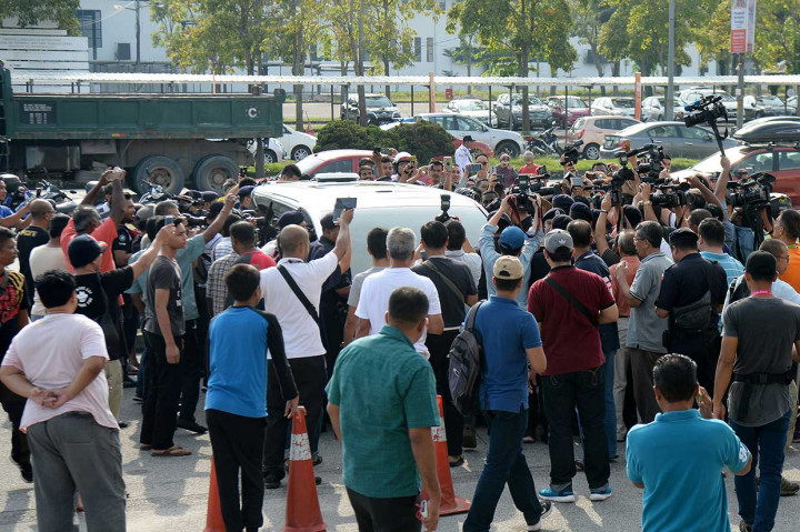 Puluhan orang mengerumuni mobil putih yang mereka duga membawa mantan PM Najib Razak saat tiba di Bandara Sultan Abdul Aziz Shah, Subang, Malaysia, Sabtu, 12 Mei 2018.