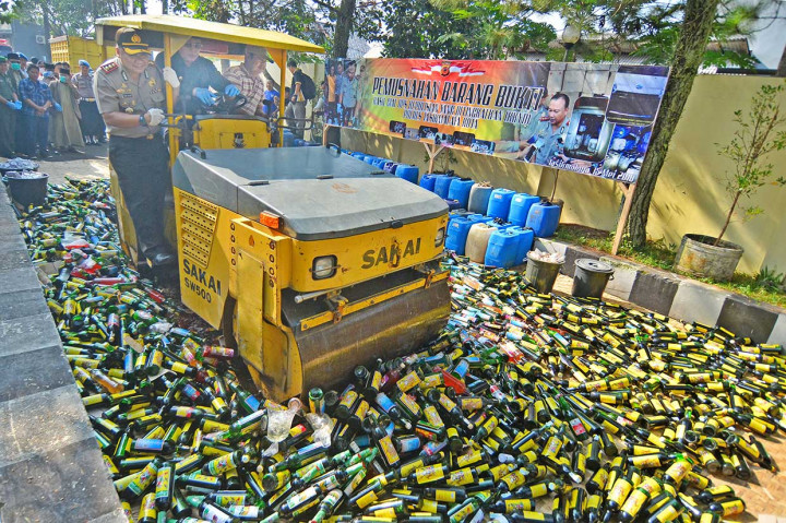 Wali Kota Tasikmalaya Budi Budiman (tengah) bersama Kapolres Kota Tasikmalaya AKBP Febry Kurniawan Ma'ruf (kiri) mengoperasikan alat berat pada pemusnahan barang bukti ribuan botol minuman keras (miras) di halaman Polres Tasikmalaya Kota, Jawa Barat, Selasa, 15 Mei 2018. ANTARA/Adeng Bustomi