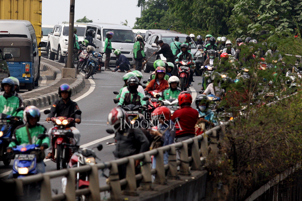 Pengendara motor menyapu paku dan memeriksa ban mereka yang bocor terkena ranjau paku yang di tebar oleh orang yang tak bertanggung jawab, di Jalan KH Abdullah Syafei, Jakarta.
