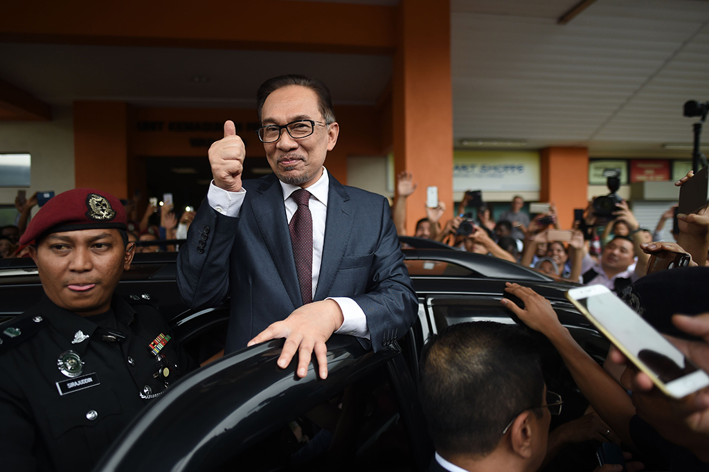 Anwar mengacungkan ibu jarinya ke arah para jurnalis yang menanti sebelum masuk mobil dan melaju tanpa memberikan komentar. AFP/MOHD RASFAN
