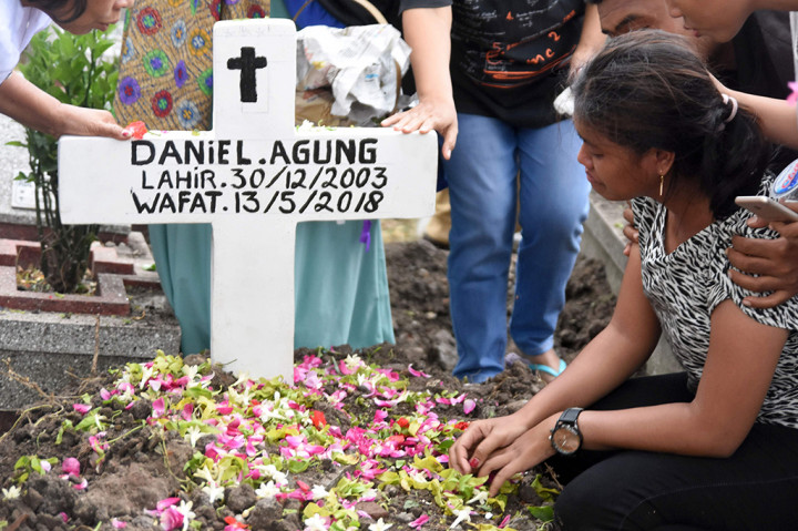 Novi (kanan) kakak dari Daniel Agung Putra Kusuma korban bom bunuh diri di Gereja Pantekosta Pusat Surabaya (GPPS) berada disamping pusara ketika pemakaman di Makam Putat Gede Surabaya, Jawa Timur, Selasa, Selasa (15/5). AFP/MICHAEL AMMAR