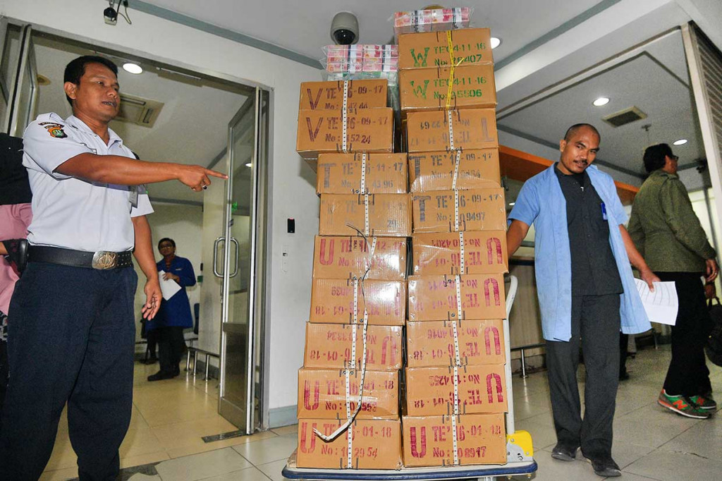 Petugas membawa tumpukan uang rupiah yang dikemas di dalam kardus di Cash Center Bank Mandiri, Jakarta, Rabu, 16 Mei 2018.