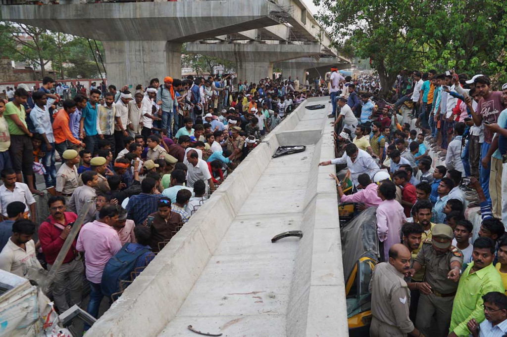 Petugas penyelamat dibantu warga berusaha mengevakuasi para korban yang terperangkap di dalam mobil yang tertimpa bongkahan beton konstruksi jembatan layang di Varanasi, sebuah kota di Negara Bagian Uttar Prades, Rabu, 16 Mei 2018.