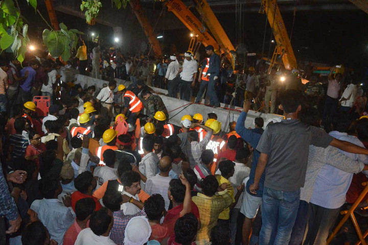Petugas dibantu alat berat mengangkat bongkahan beton konstruksi jembatan layang untuk mengevakuasi para korban.