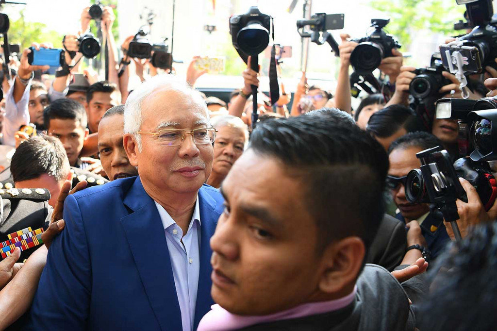Najib Razak dengan mengenakan baju biru tiba di KPK Malaysia dengan mengendarai Toyota Velfire warna putih dengan diiringi dua mobil, disambut puluhan pendukungnya di depan pintu masuk Kantor SPRM.