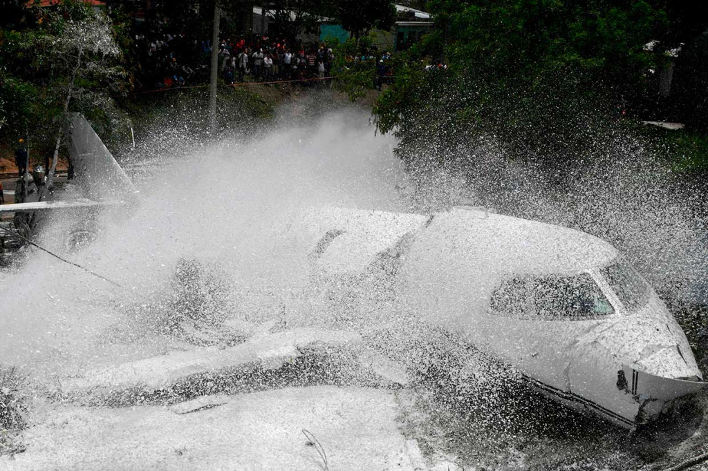 Petugas pemadam kebakaran menyemprotkan busa ke badan pesawat, setelah tergelincir dari landasan pacu di Bandara Internasional Tocontin, Tegucigalpa pada Selasa, 22 Mei 2018 waktu setempat.