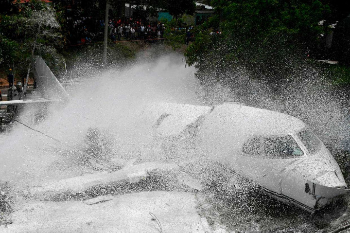 Petugas pemadam kebakaran menyemprotkan busa ke badan pesawat, setelah tergelincir dari landasan pacu di Bandara Internasional Tocontin, Tegucigalpa pada Selasa, 22 Mei 2018 waktu setempat.