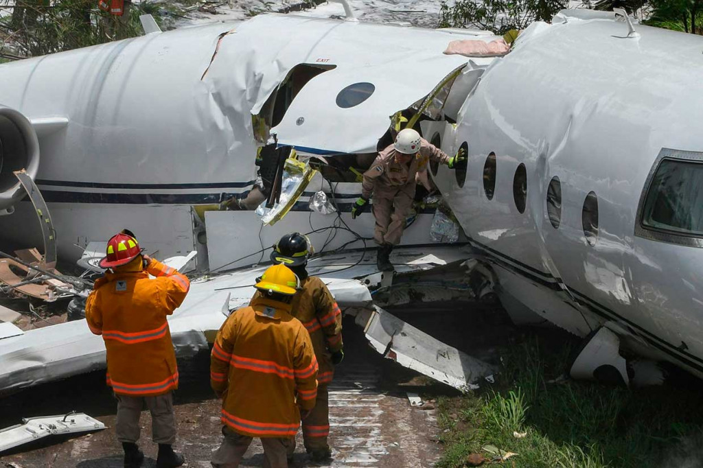 Petugas memeriksa badan pesawat yang terbelah untuk mencari penumpang dan awak pesawat yang terjebak di dalamnya.