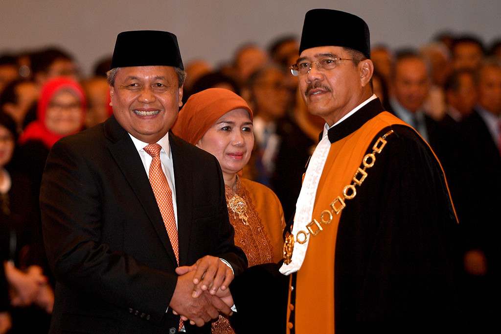 Ketua Mahkamah Agung Hatta Ali (kanan) memberikan ucapan selamat kepada Gubernur Bank Indonesia Perry Warjiyo (kiri) usai pengucapan sumpah jabatan pelantikan di Mahkamah Agung, Jakarta.
