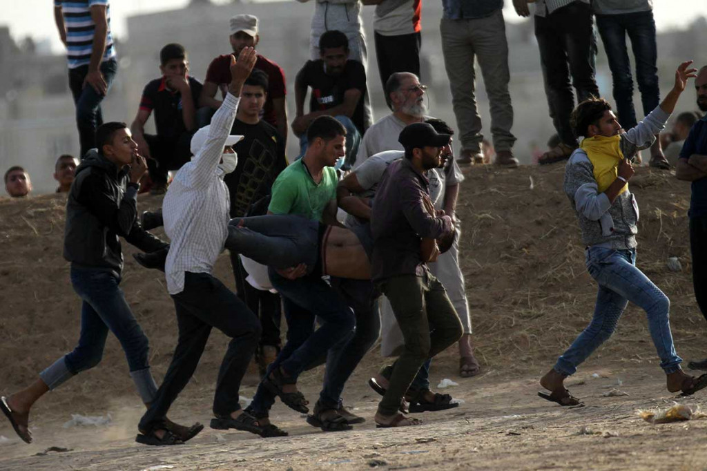 Pemprotes Palestina mengevakuasi rekan mereka yang terluka akibat tembakan tentara Israel selama bentrokan di sepanjang perbatasan Jalur Gaza-Israel, di Khan Yunis, Jumat, 25 Mei 2018.