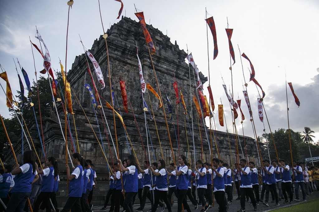Mereka lalu menuju ke tenda di pelataran Candi Mendut untuk menyalakan lilin pancawarna. Di depan altar besar dengan patung Sang Buddha dan hiasan aneka bunga dan buah-buahan di tenda itu, secara bergantian mereka membacakan parita atau doa-doa dalam ajaran Buddha.