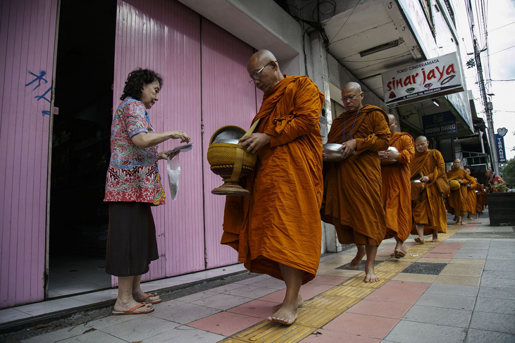 Puluhan warga yang sudah menunggu di sepanjang jalan, mengisi periuk-periuk itu dengan berbagai sedekah, seperti uang, makanan, dan minuman.