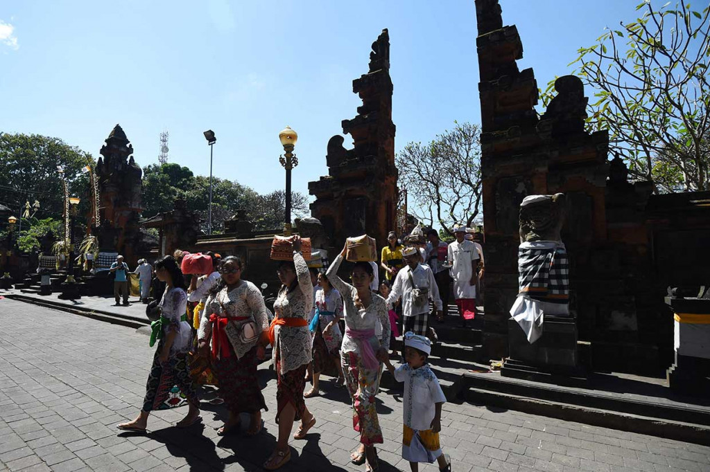 Umat Hindu baik pria, wanita, dan anak-anak pada hari istimewa itu mengenakan busana adat nominasi warna putih dan wanita menjunjung sesajen (sesaji) pergi ke Pura Jagatnatha, Denpasar, untuk mengadakan persembahyangan. AFP Photo/Sonny Tumbelaka