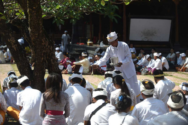 Seorang pemuka agama Hindu memercikkan air suci kepada umat saat persembahyangan Hari Raya Galungan di Pura Jagatnatha, Denpasar.  di Pura Jagatnatha, Denpasar. AFP Photo/Sonny Tumbelaka