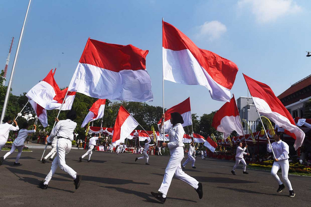 Sejumlah pelajar membawa bendera merah putih saat upacara hari jadi Kota Surabaya yang ke-725.