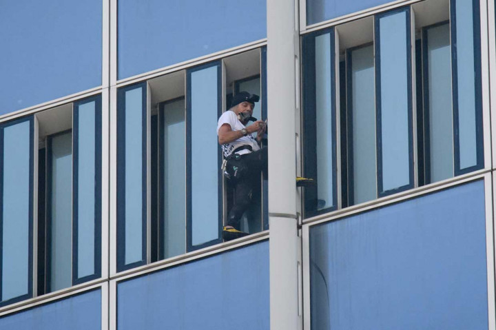 Pria berusia 55 tahun tersebut menapaki bangunan dengan tangan kosong dan tanpa tali pengamana ketika staf mengejarnya dari dalam.