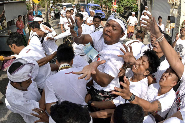 Warga berebut uang yang dibagikan saat Tradisi Mesuryak di Desa Bongan, Tabanan, Bali, Sabtu, 9 Juni 2018. 