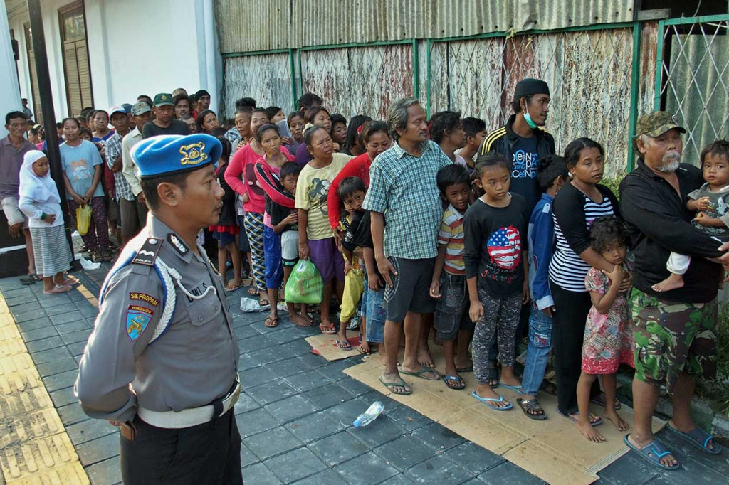 Aparat kepolisian berjaga-jaga mengatur antrean calon penerima zakat agar tertib dan tidak saling serobot.