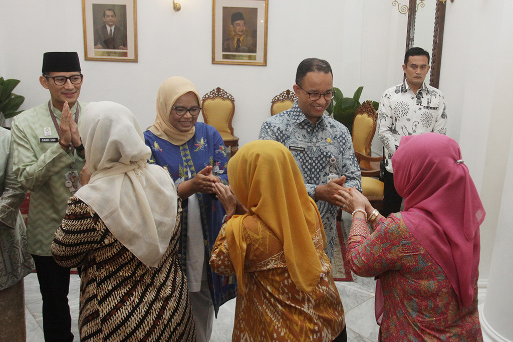 Gubernur DKI Jakarta Anies Baswedan (ketiga kanan) dan Wakil Gubernur Sandiaga Uno (kiri) bersalaman dengan pegawai Pemprov DKI dan warga Jakarta saat halal bihalal, di Balaikota, Jakarta. Antara Foto/ Reno Esnir