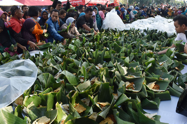 Warga antre untuk mendapatkan nasi pecel gratis saat digelar Festival Pecel Pincuk di Kota Madiun, Jawa Timur.