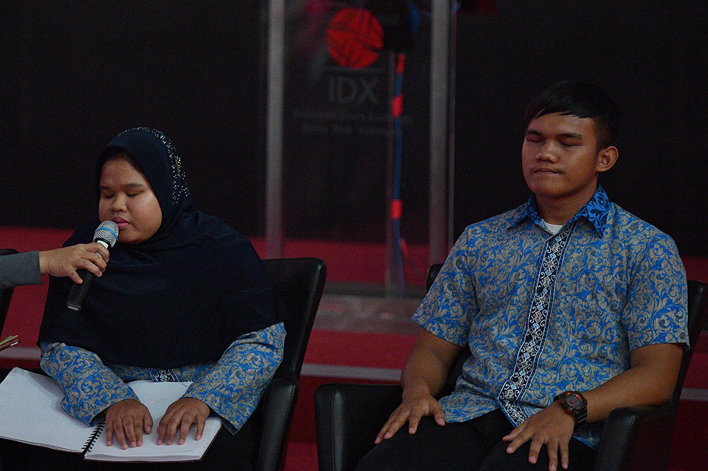 Dua penyandang disabilitas dari Panti Sosial Bina Netra (PSBN) Wyata Guna Bandung, Wigya Desi Amalia (kiri) dan Elda Fahmi membacakan isi buku Yuk Nabung Saham versi braille yang diluncurkan di Bursa Efek Indonesia, Jakarta.