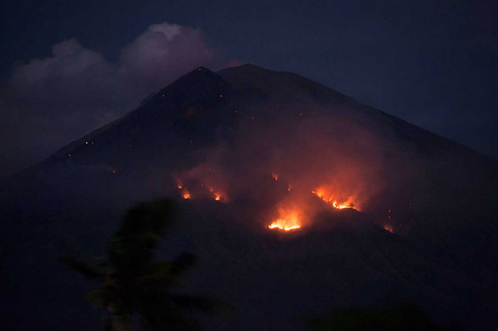 Api membakar hutan lereng Gunung Agung setelah terjadinya lontaran batu pijar dari kawah, terlihat dari Desa Culik, Karangasem, Bali, Selasa, 3 Juli 2018. Antara Foto/Nyoman Budhiana