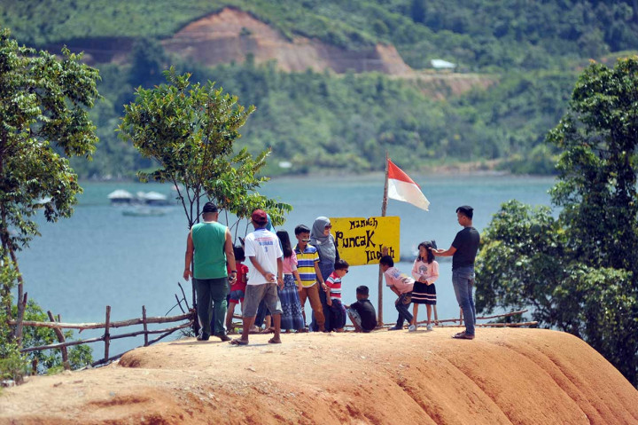 Wisatawan berfoto dengan latar belakang panorama KWBT Mandeh di Kabupaten Pesisir Selatan.