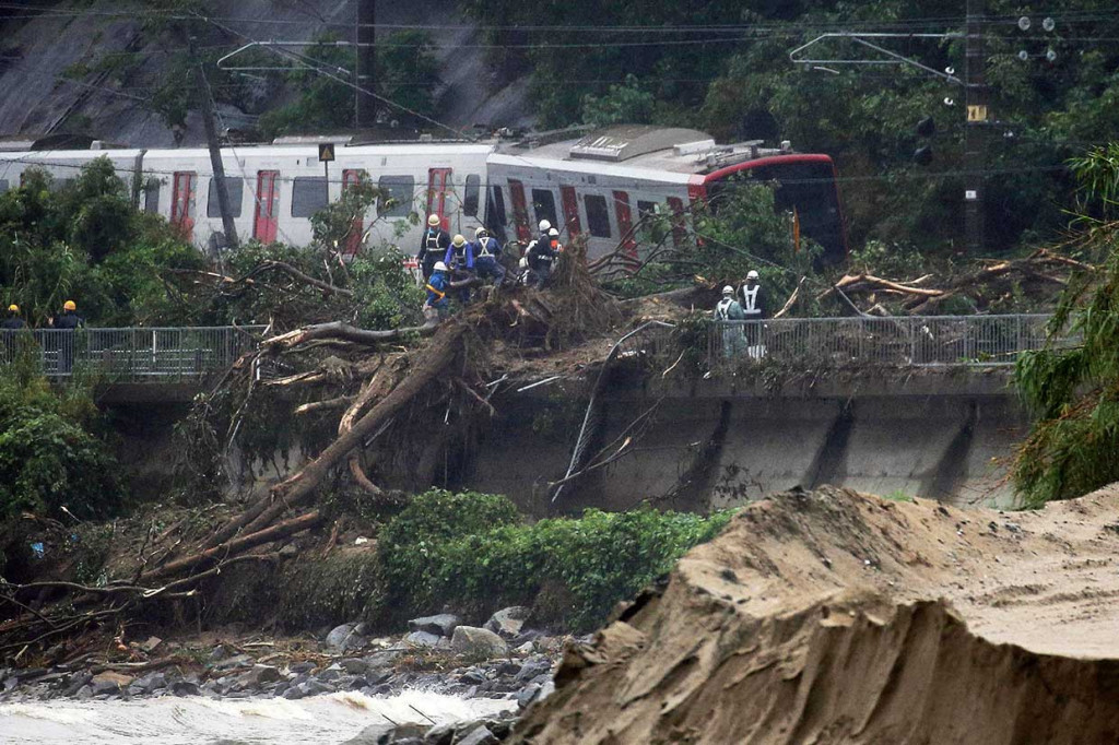 Petugas tengah menyingkirkan tanah dan pohonan yang tumbang akibat longsor di Karatsu, Prefektur Saga. Longsor mengakibatkan jalur kereta api terputus.