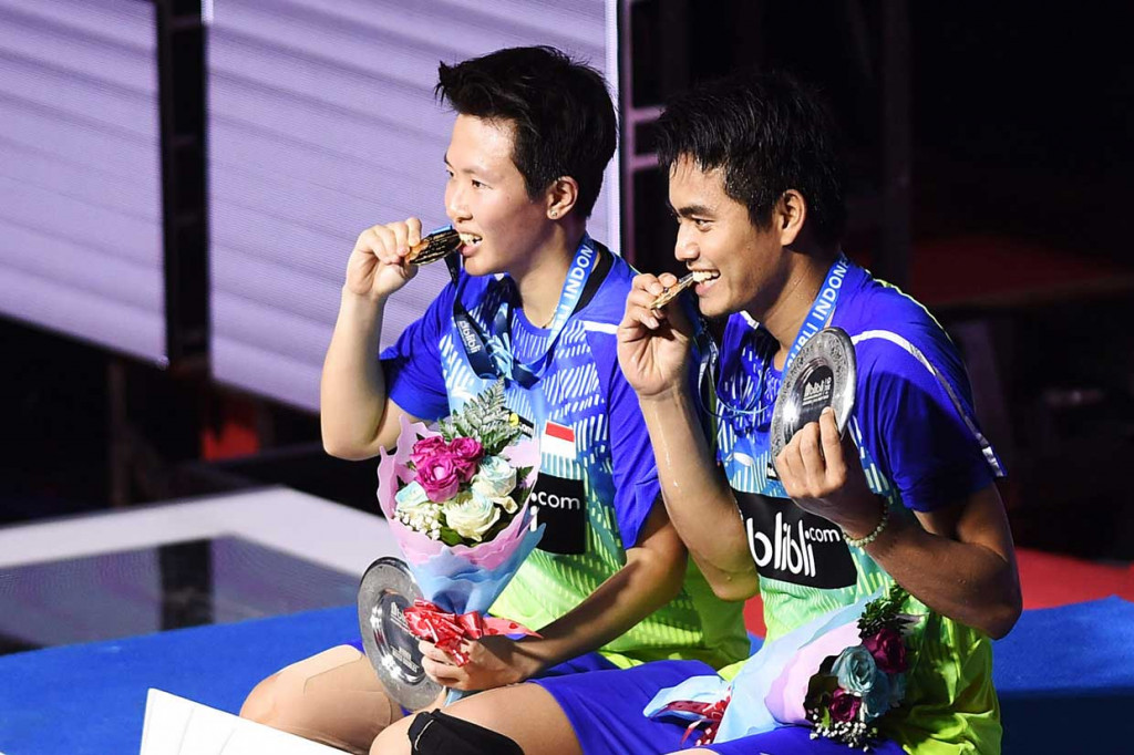 Ganda campuran Indonesia Tontowi Ahmad (kanan) dan Liliyana Natsir menggigit medali usai menang atas ganda Malaysia Chan Peng Soon/Goh Liu Ying dalam partai final Blibli Indonesia Open 2018 di Jakarta, Minggu, 8 Juli 2018. 
