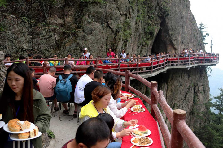 Para pengunjung menikmati makanan di jalanan selebar sekitar 2 meter yang menempel di tebing setinggi 2.000 meter di atas permukaan laut.