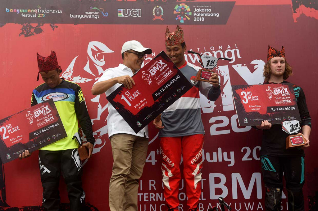 Bupati Banyuwangi Abdullah Azwar Anas (kedua kiri) menyerahkan hadiah juara pertama kepada atlet sepeda BMX Indonesia National Team putra I Gusti Bagus Saputra (kedua kanan) pada kejuaraan BMX Banyuwangi Internasional 2018 di Sirkuit Muncar, Banyuwangi, Jawa Timur, Minggu, 15 Juli 2018.