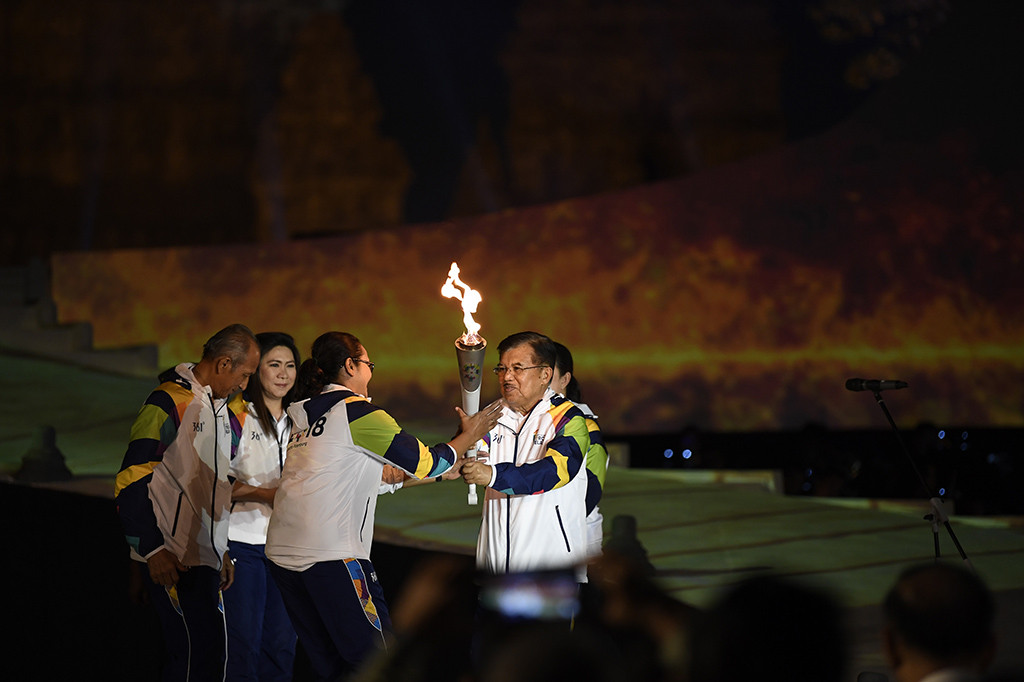 Susi dan Yustedjo kemudian membawa turun api obor Asian Games yang telah disatukan dari atas panggung utama. Susi dan Yustedjo lalu menyerahkannya kepada JK.
