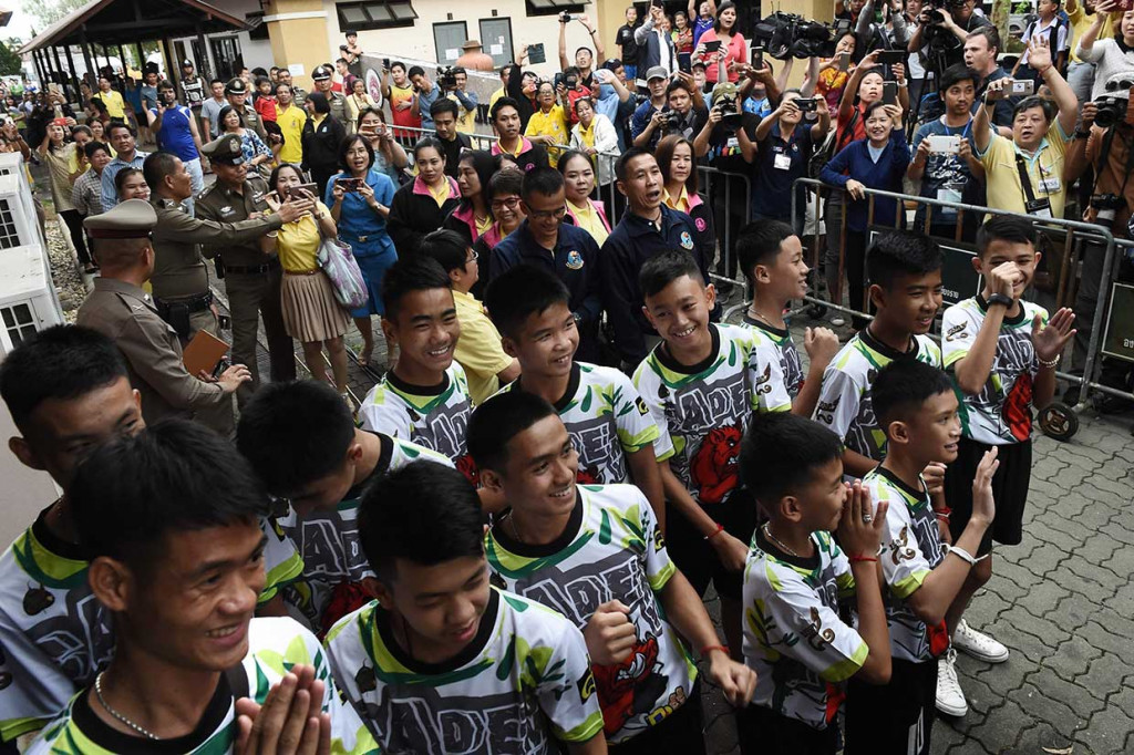 12 remaja dan pelatih sepak bola yang diselamatkan dari gua banjir di Thailand, melambai, tersenyum, serta memberikan salam adat 'wai' saat  menghadiri konferensi pers pertama mereka di Chiang Rai, Rabu, 18 Juli 2018.