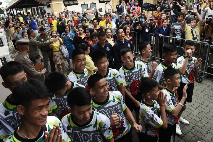 12 remaja dan pelatih sepak bola yang diselamatkan dari gua banjir di Thailand, melambai, tersenyum, serta memberikan salam adat 'wai' saat  menghadiri konferensi pers pertama mereka di Chiang Rai, Rabu, 18 Juli 2018.