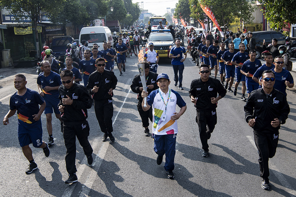 Komisaris Independen Mandiri Inhealth Ali Ghufron Mukti (tengah) membawa obor saat prosesi Torch Relay Asian Games 2018 melintasi kawasan Jalan MT Haryono, Yogyakarta, DI Yogyakarta.