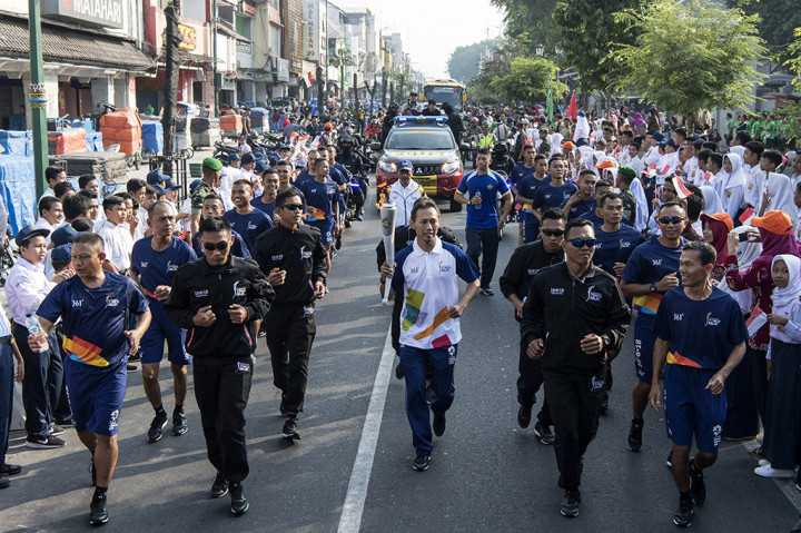 Mantan pebulu tangkis Sigit Budiarto (tengah) membawa obor saat prosesi Torch Relay Asian Games 2018 melintasi kawasan Malioboro, Yogyakarta, DI Yogyakarta.