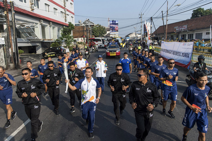 Penyanyi Rio Febrian (tengah) membawa obor saat prosesi Torch Relay Asian Games 2018 melintasi kawasan Pasar Kembang, Yogyakarta, DI Yogyakarta.
