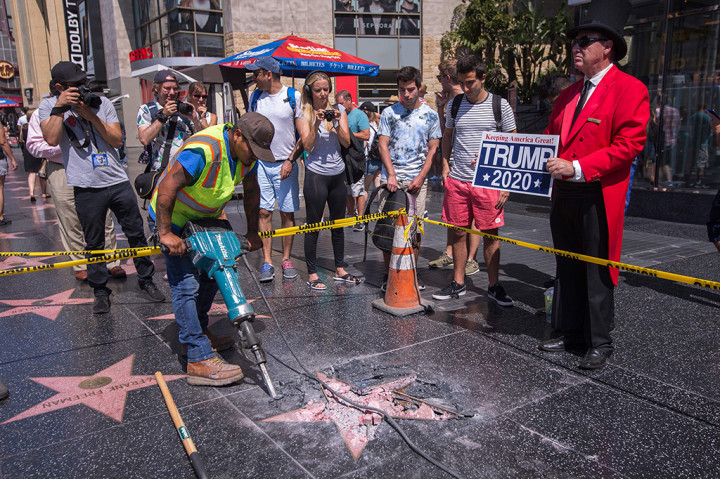 Pengunjung mengambil gambar bintang di Walk of Fame Donald Trump. Bagian tengah bintang yang berwarna merah itu telah hancur menjadi serpihan pasir dan batu.
