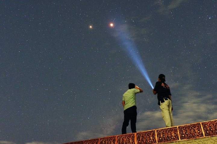 Warga menyaksikan pemandangan planet Mars berdampingan dengan gerhana bulan total terlihat di Kota Padang, Sumatera Barat. Antara/Iggoy El Fitra