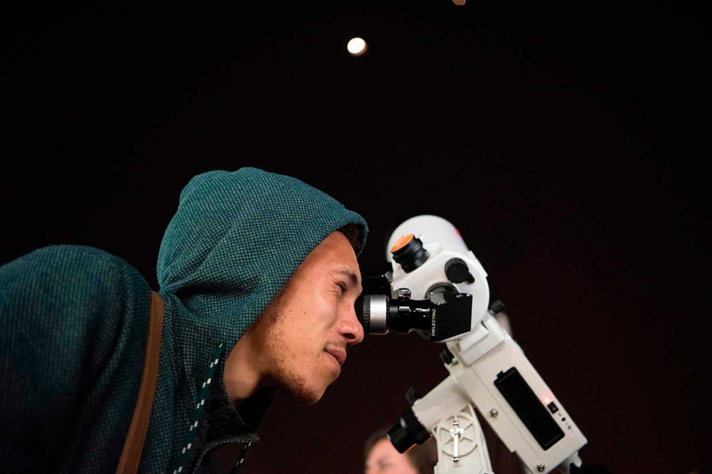 Seorang pria melihat gerhana bulan total melalui teleskop di Cape Town, Afrika Selatan. AFP Photo/Rodger Bosch