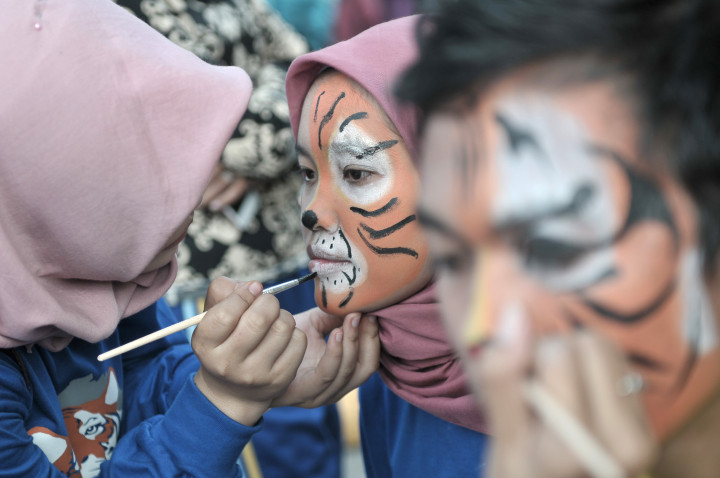 Relawan melukis wajah pengunjung saat kampanye peringatan Hari Harimau Sedunia di Jambi. Kegiatan tersebut bertujuan mengampanyekan penyelamatan Harimau Sumatra (Panthera tigris sumatrae). Antara Foto/Wahdi Septiawan