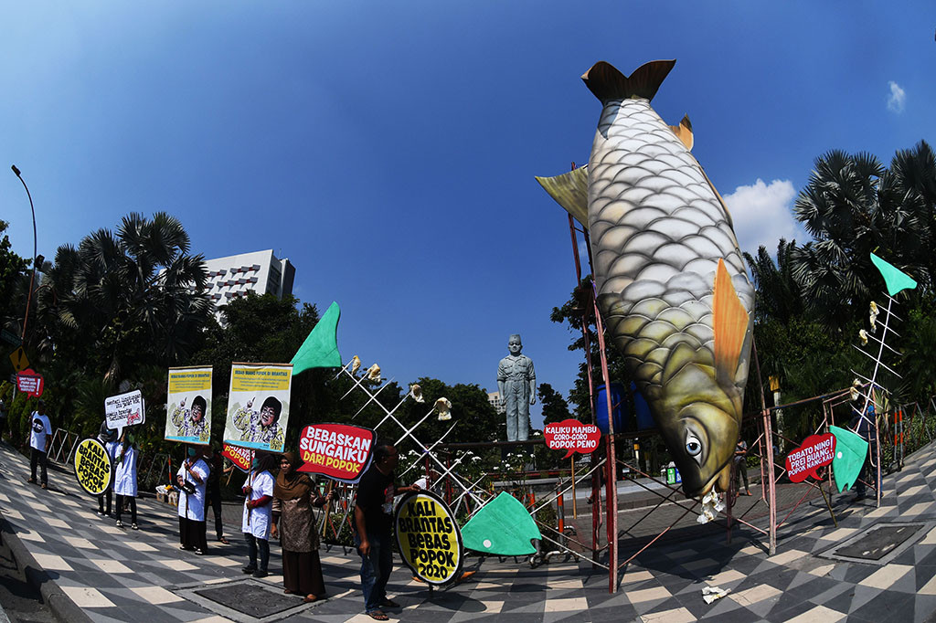 Aktivis lingkungan yang tergabung dalam Ecoton mengangkat poster di samping replika ikan yang telah tercemar limbah popok saat menggelar aksi di Surabaya, Jawa Timur.
