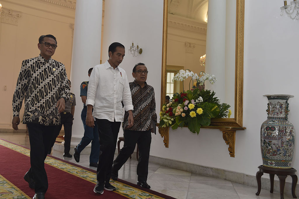 Presiden Joko Widodo (tengah) didampingi Mensesneg Pratikno (kanan) dan Bupati Bantaeng Nurdin Abdullah (kiri) berjalan menuju ruang Garuda untuk menerima sejumlah bupati dalam audiensi di Istana Bogor, Jawa Barat.