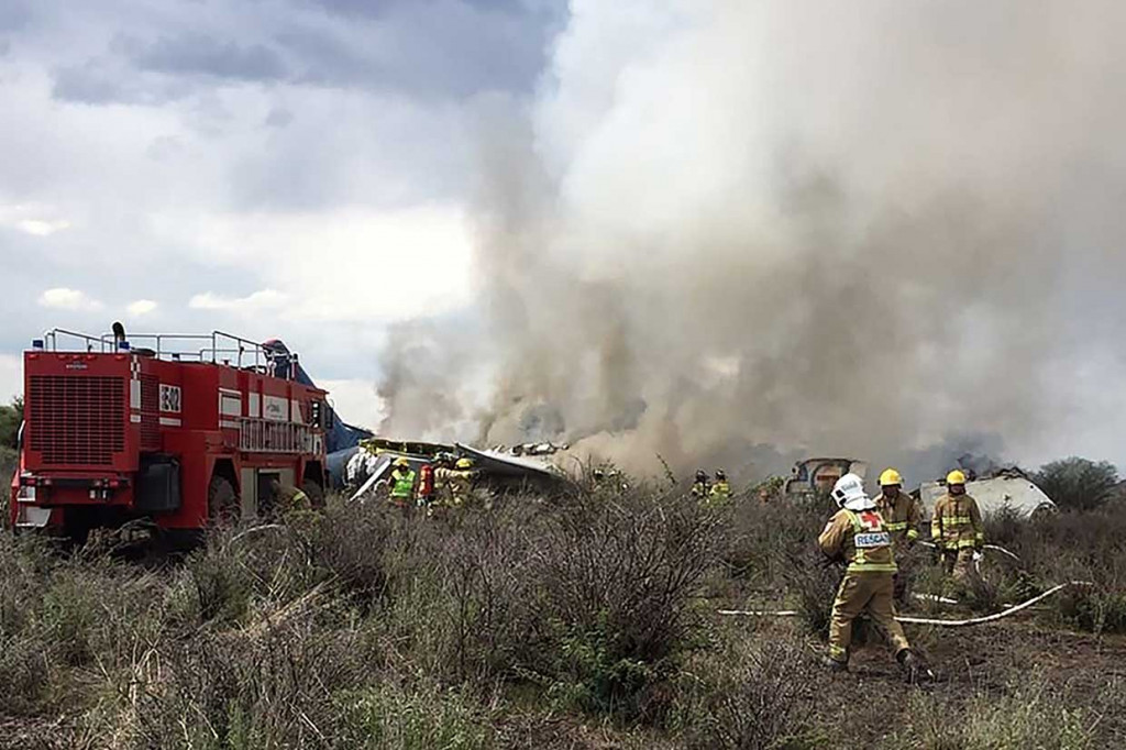 Api muncul dari badan pesawat usai mendarat darurat, dan belasan penumpang bergegas lari meninggalkan tempat kejadian yang diliputi asap, sementara petugas pemadam kebakaran berjibaku memadamkan api.