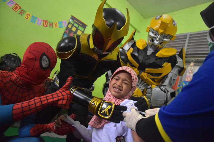 Seorang anak ditemani komunitas kostum superhero Spiderman, Kamen Raider, dan Bumblebee saat imunisasi campak (measles) dan rubella (MR) di SDN 2 Kota Pekanbaru, Riau, Rabu, 1 Agustus 2018. Antara Foto/FB Anggoro
