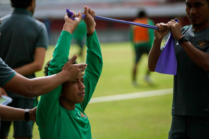 Irfan Jaya melakukan peregangan otot.