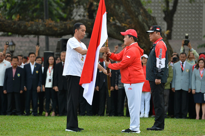 Presiden Joko Widodo (kiri) menyerahkan bendera Merah Putih kepada Ketua Komite Olahraga Indonesia (KOI) Erick Thohir (tengah) disaksikan CdM kontingen Indonesia, Komjen Pol Syafruddin saat upacara pelepasan di halaman tengah Kompleks Istana, Jakarta.