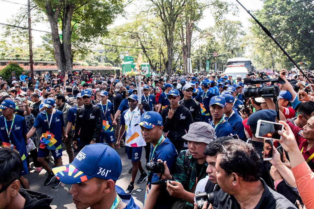 Pemain sepak bola tim nasional era 90-an Alexander Pulalo (tengah) membawa obor saat prosesi Torch Relay Asian Games 2018 melintasi kawasan Gedung Sate.