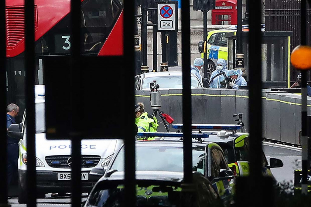 Petugas kepolisian melakukan olah tempat kejadian perkara (TKP) sebuah mobil yang menabrak pembatas jalan di luar Gedung Parlemen Inggris di London, Selasa, 14 Agustus 2018.